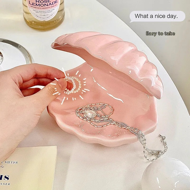 White and pink porcelain shell-shaped tray with integrated yellow LED night light on a wooden table.