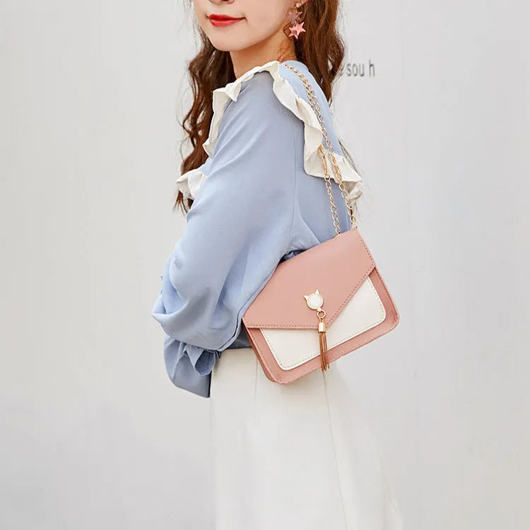 Small square PU leather messenger bag with cat tassel decoration and chain strap on a white background