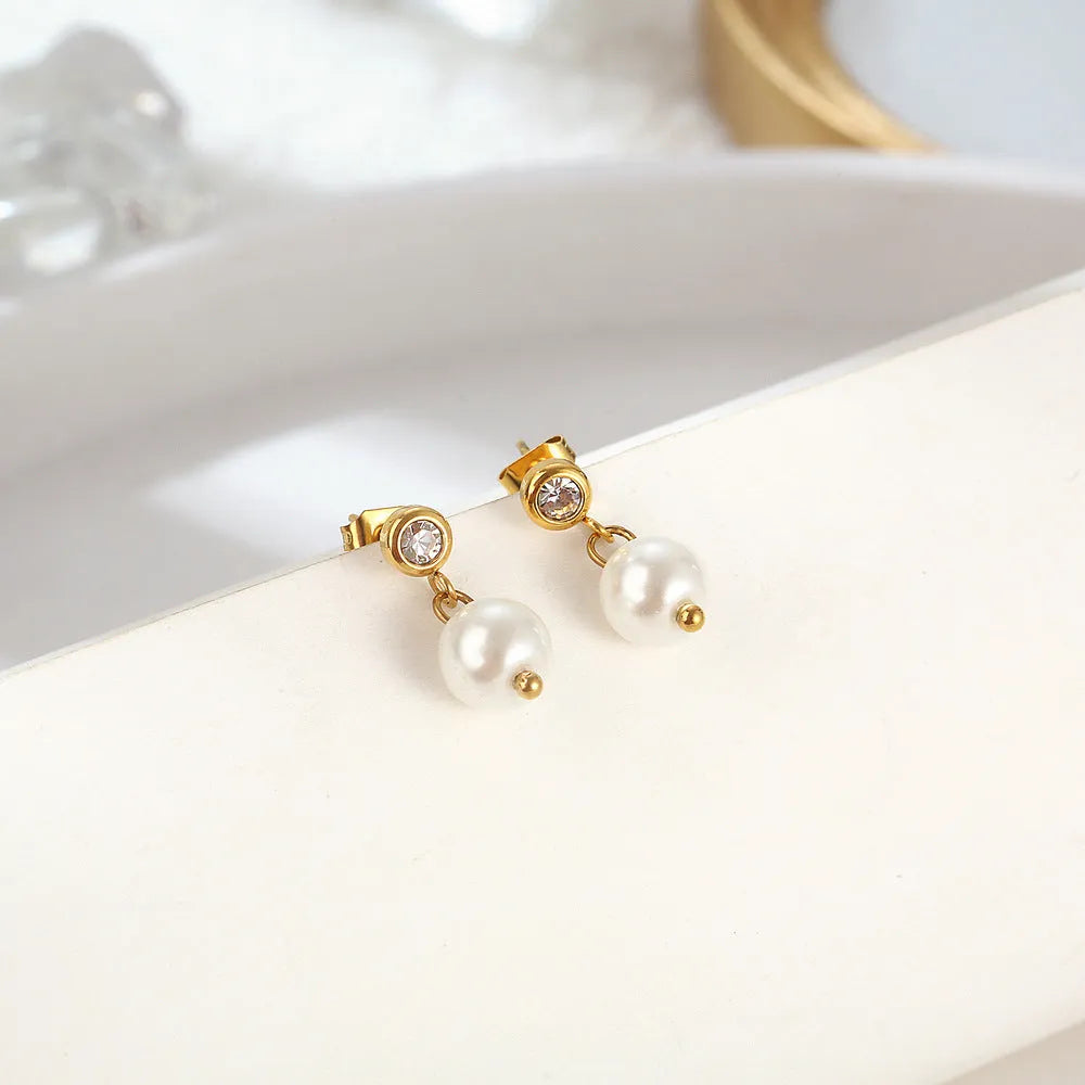 Women's gold titanium steel C-shaped earrings with pearl inlay flower design on white background
