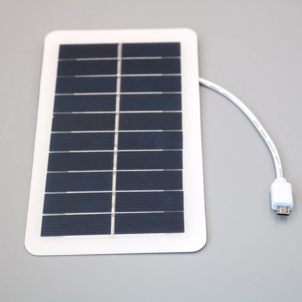 Black portable solar panel charger with USB port for mobile phones on a textured surface.