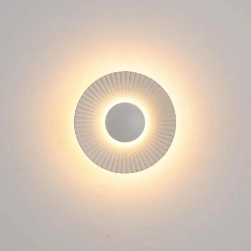 Round aluminium wall lamp in an outer white and inner gold colour combination, mounted on a wall.
