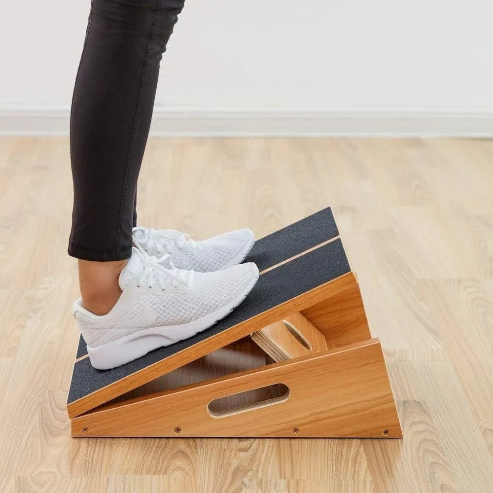 Wooden adjustable angle stretch board in wood colour on a gym floor