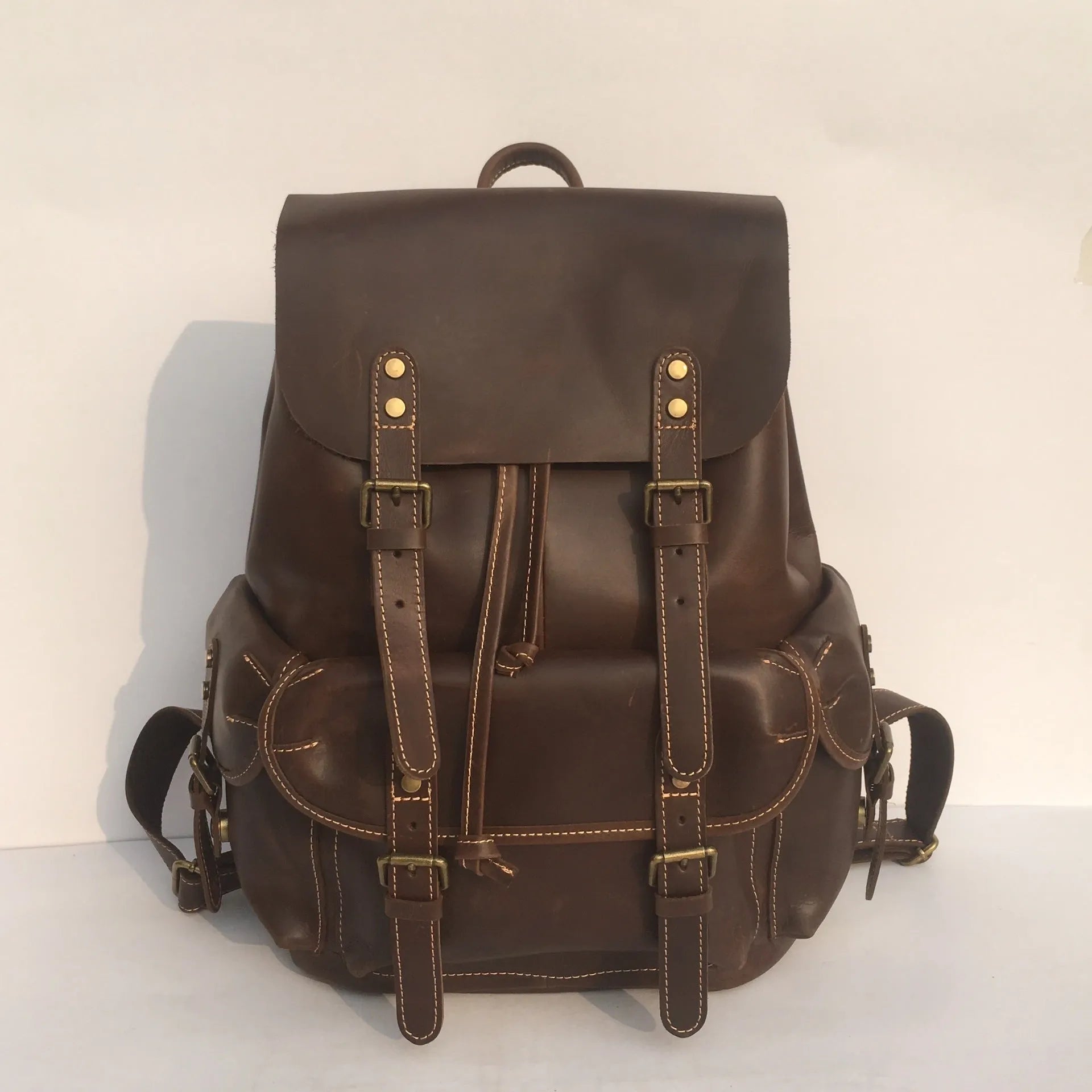 Brown leather men's backpack with shoulder straps showing cowhide leather texture