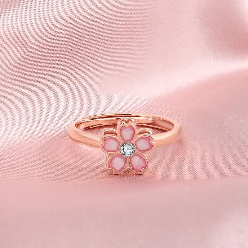 Cherry blossom rotatable ring with rose gold finish, adjustable opening, and silver base shown on a finger