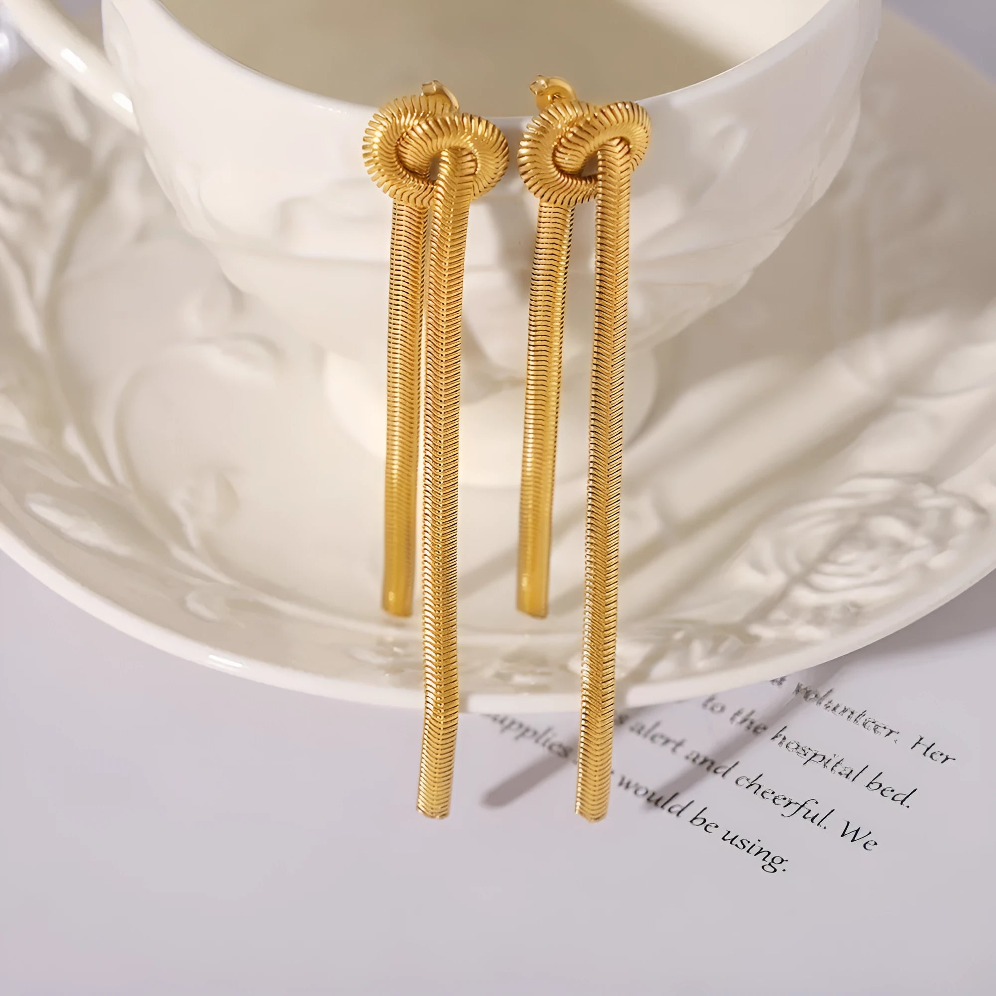 Gold titanium steel knotted tassel necklace and matching earrings set on white background