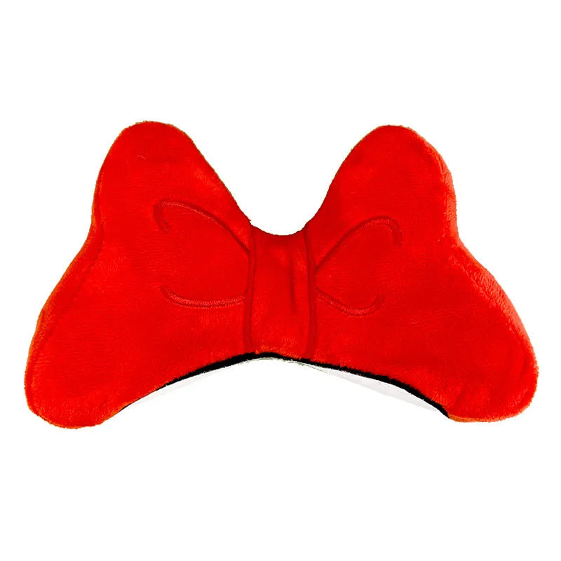 Close-up of a red plush bow decoration with a metal clip, shown next to a motorcycle helmet.
