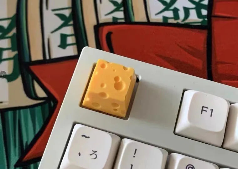 Yellow resin mechanical keyboard keycap sculpted like a wedge of Swiss cheese.