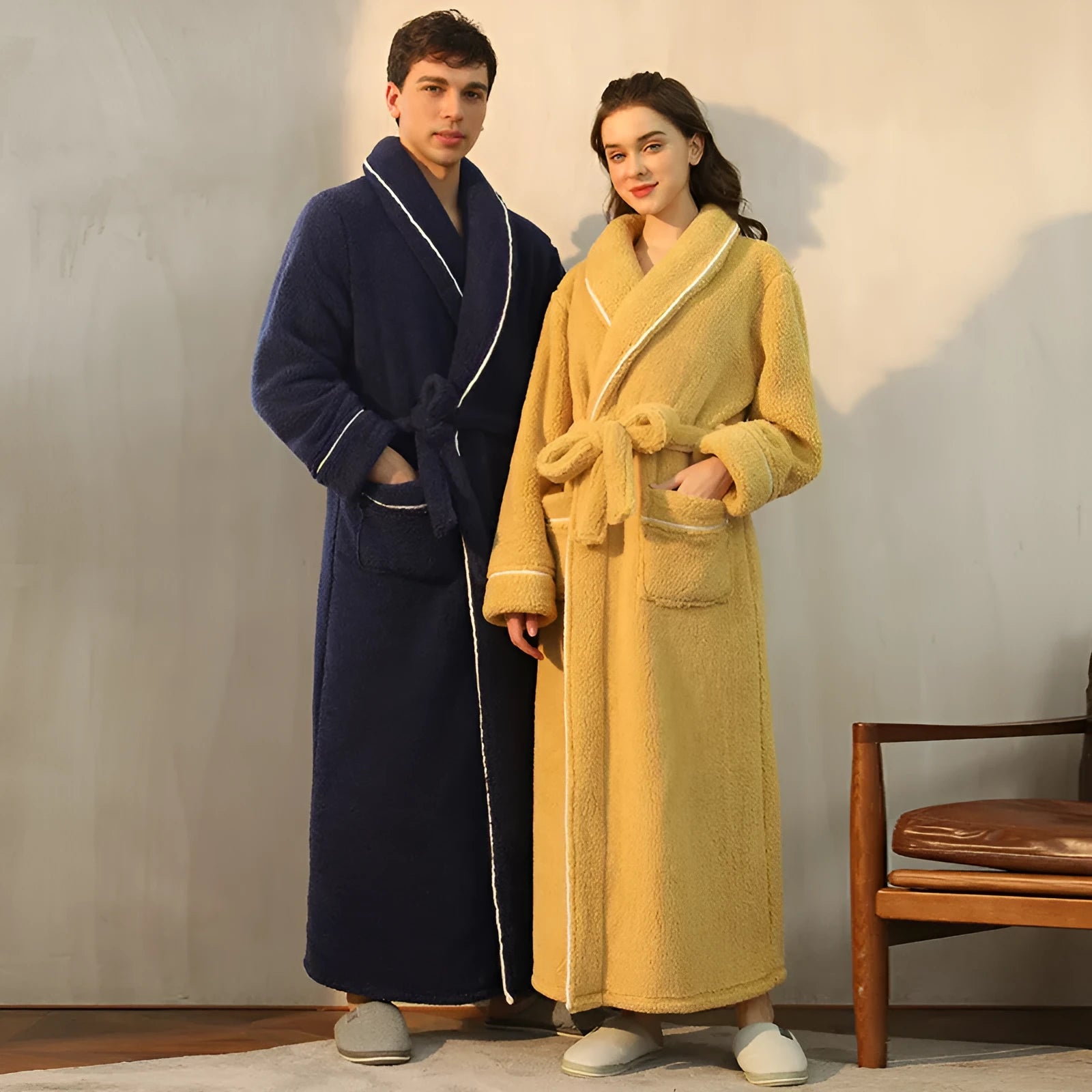 A man and woman wearing matching thick navy blue flannel nightgown robes in a winter home setting.