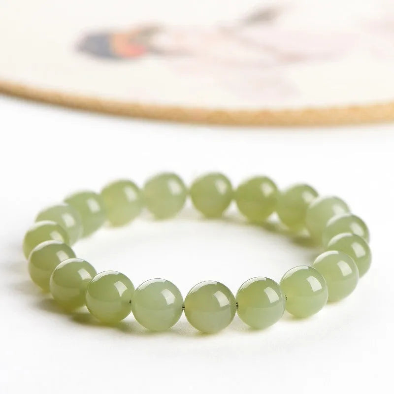 Polished Hetian jade ball bracelet on a wrist, showing spherical beads in a clear, ice-like colour.