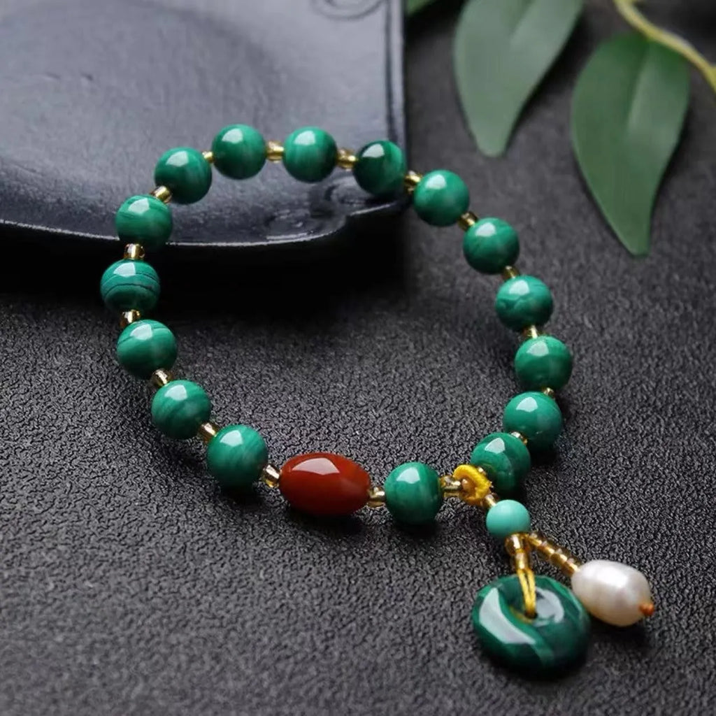 Close-up of a natural malachite and red agate bracelet with 7-8mm barrel beads on a wrist.