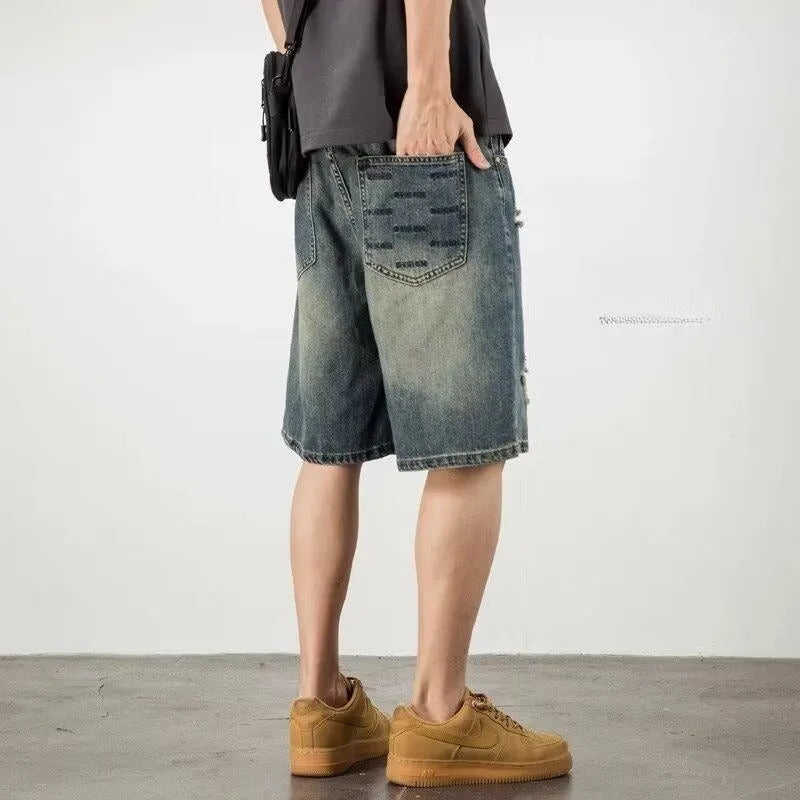 Man wearing blue retro loose hole distressed denim shorts with a straight leg cut