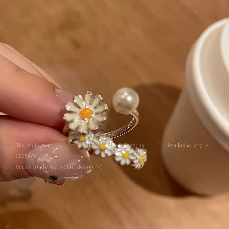 Women's copper opening ring with floral daisy charm and pearl accents on finger