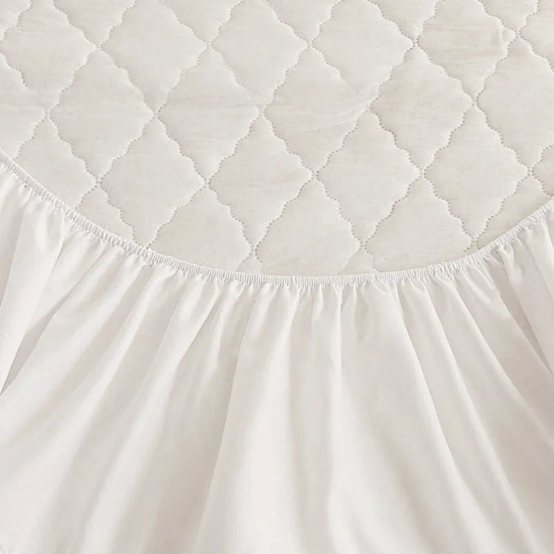 Diamond quilted black waterproof mattress protector fitted sheet and pillowcases set on a bed