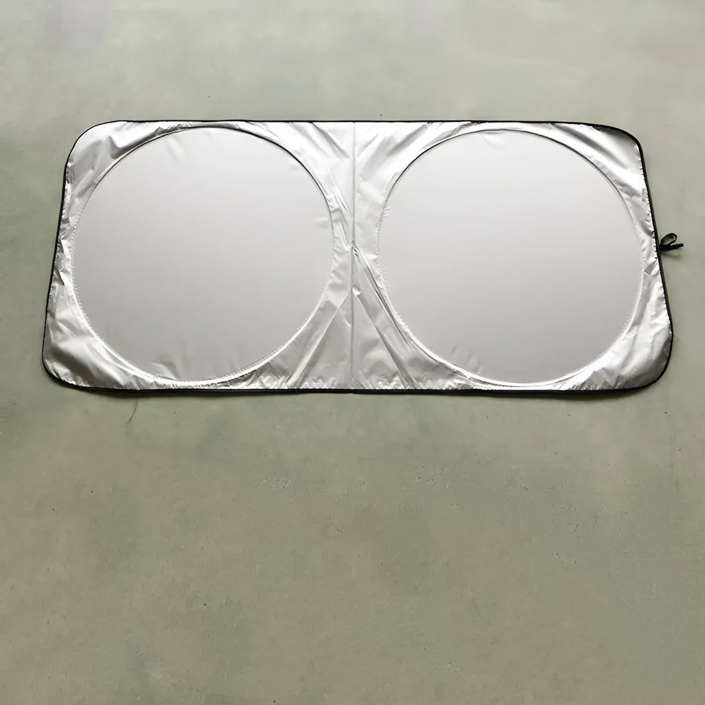 Large silver reflective car sunshade folded next to its cloth storage bag