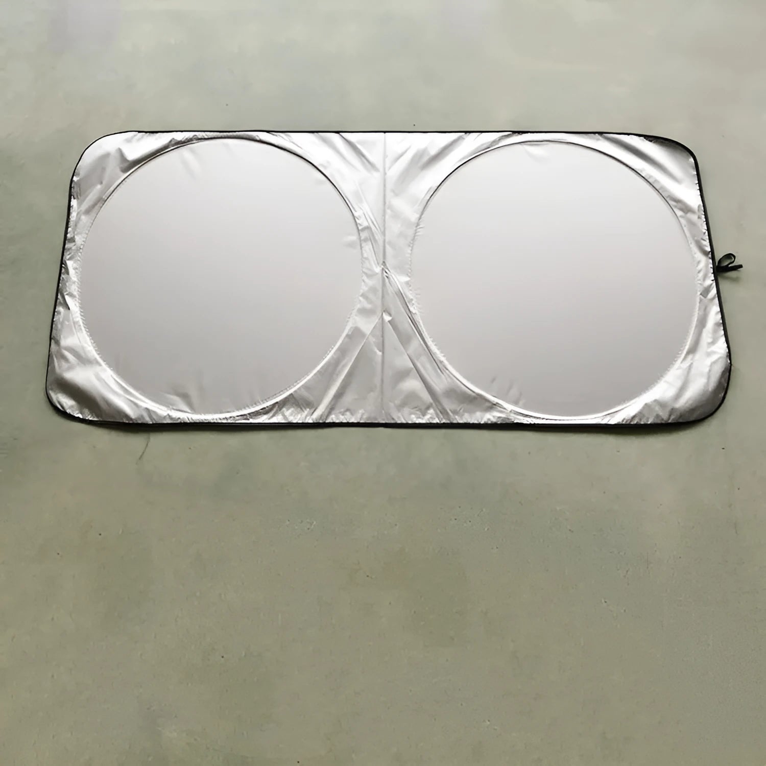 Large silver reflective car sunshade folded next to its cloth storage bag