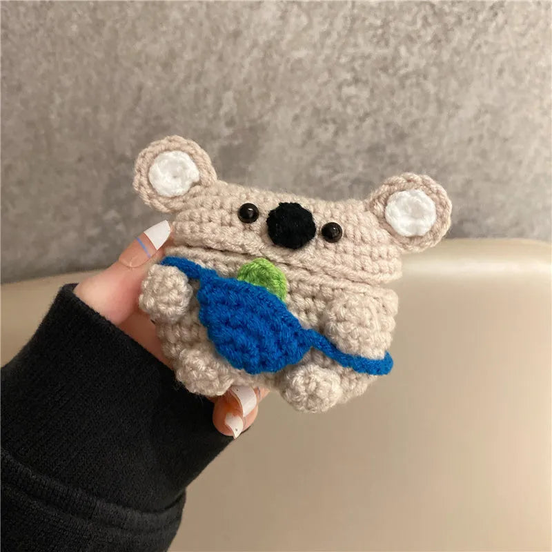 Handmade knitted AirPods case shaped like a backpack with koala ears on a blue background.