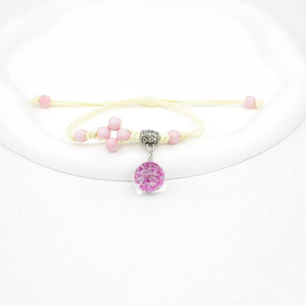 Hand-woven glass bracelet with real dried flowers inside, showing large 1.4cm beads in a blue colour.