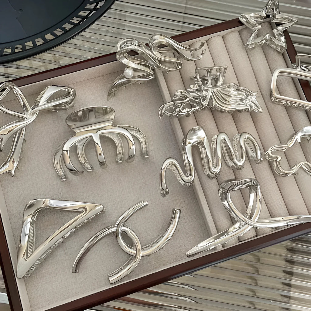 Silver metal hair claw barrette showing one of 45 designs, such as a bow or rose, on a white background.