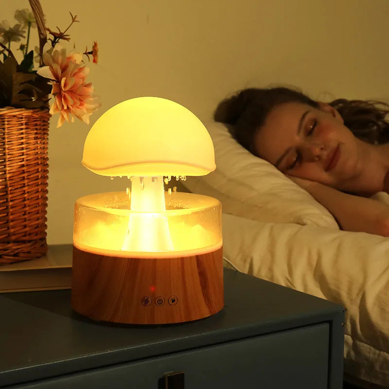White plastic rain cloud humidifier with mist and coloured night light on a wooden surface