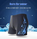 Men's plus-size blue fire pattern boxer swim trunks laid flat, with matching swimming cap.