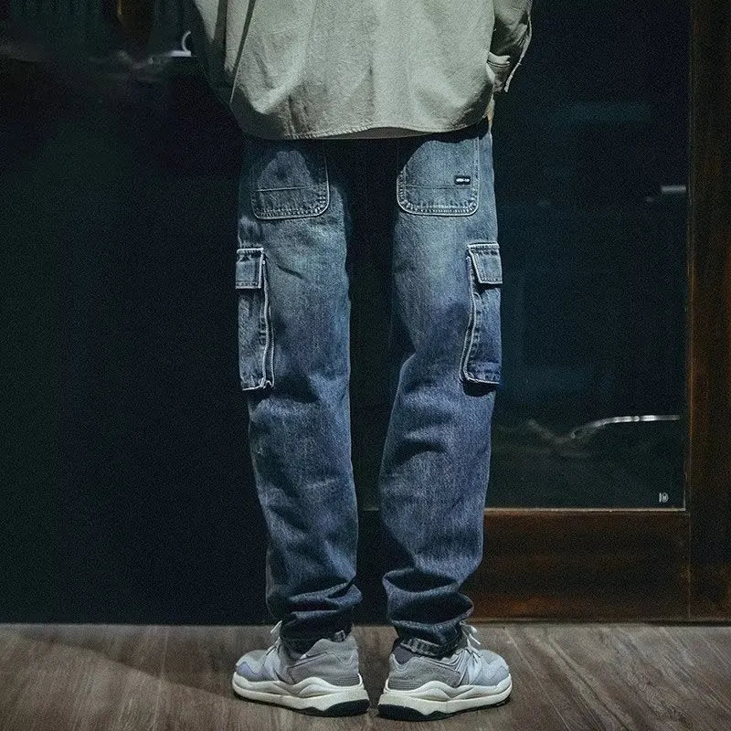 Blue men's loose straight-leg stretch denim trousers on a hanger, showing zip fly placket detail.