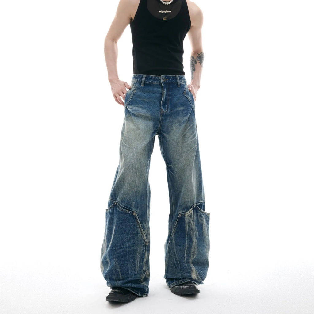Man wearing verdant blue loose-fit retro jeans with a distinctive white burst pattern wash and a curved knife leg cut.