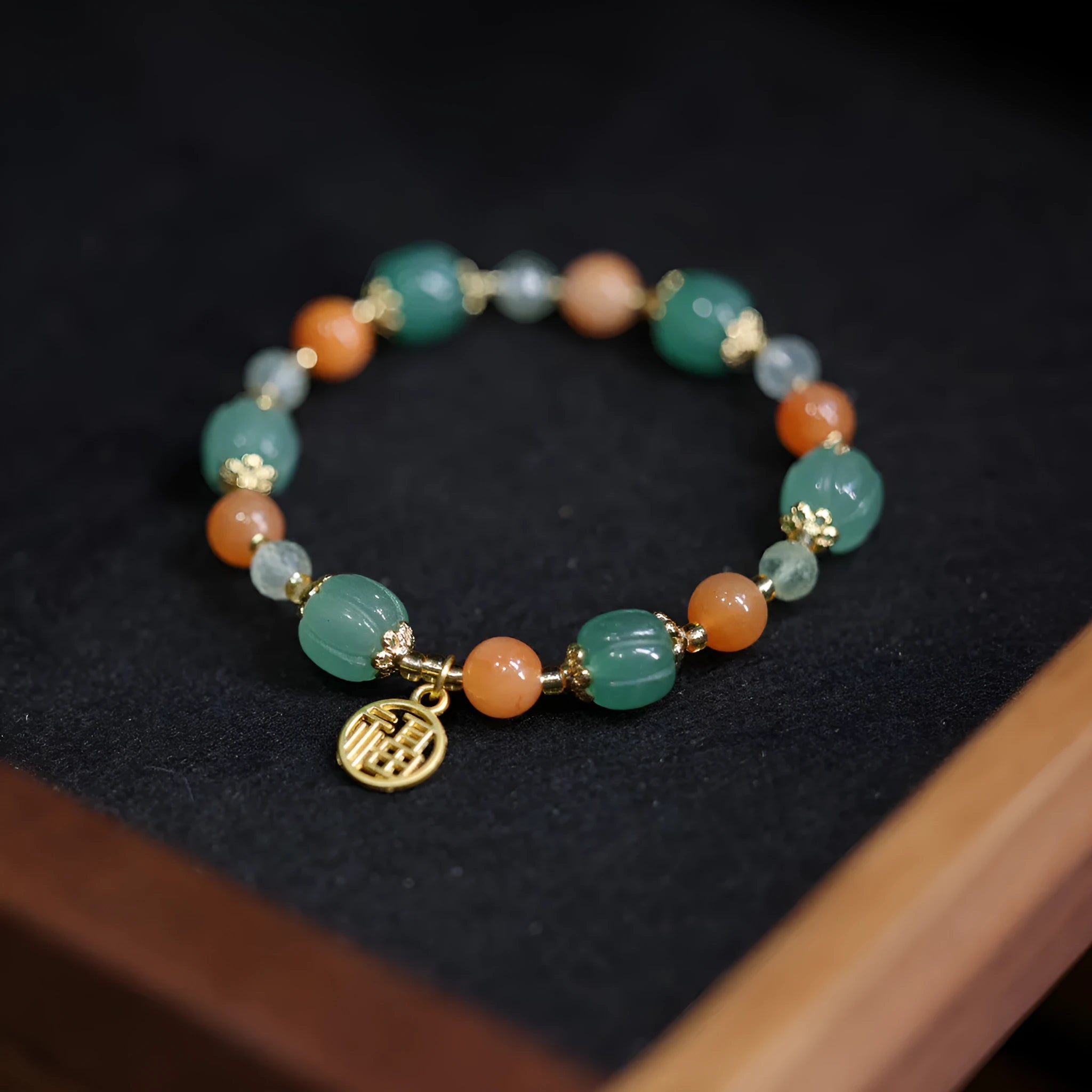 Close-up of a jade and prehnite Chinese-style pumpkin bead bracelet on a wrist.