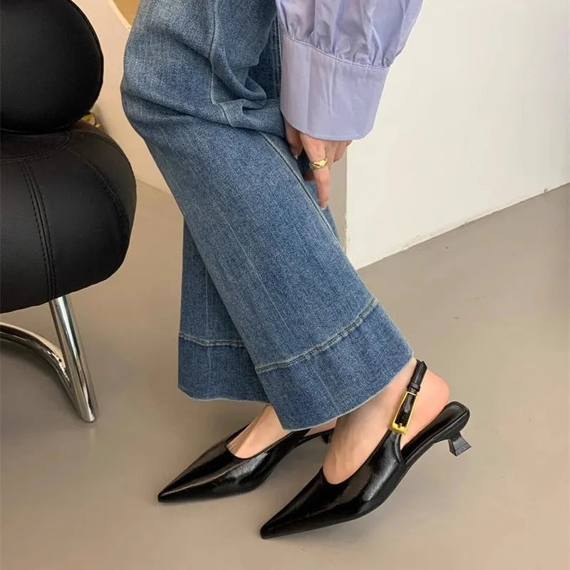 Women's black pointed toe low heel shoes with an ankle strap and rubber sole.