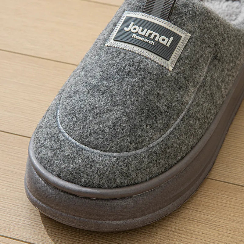 Men's brown and grey suede slippers with a thick sole on a plain background