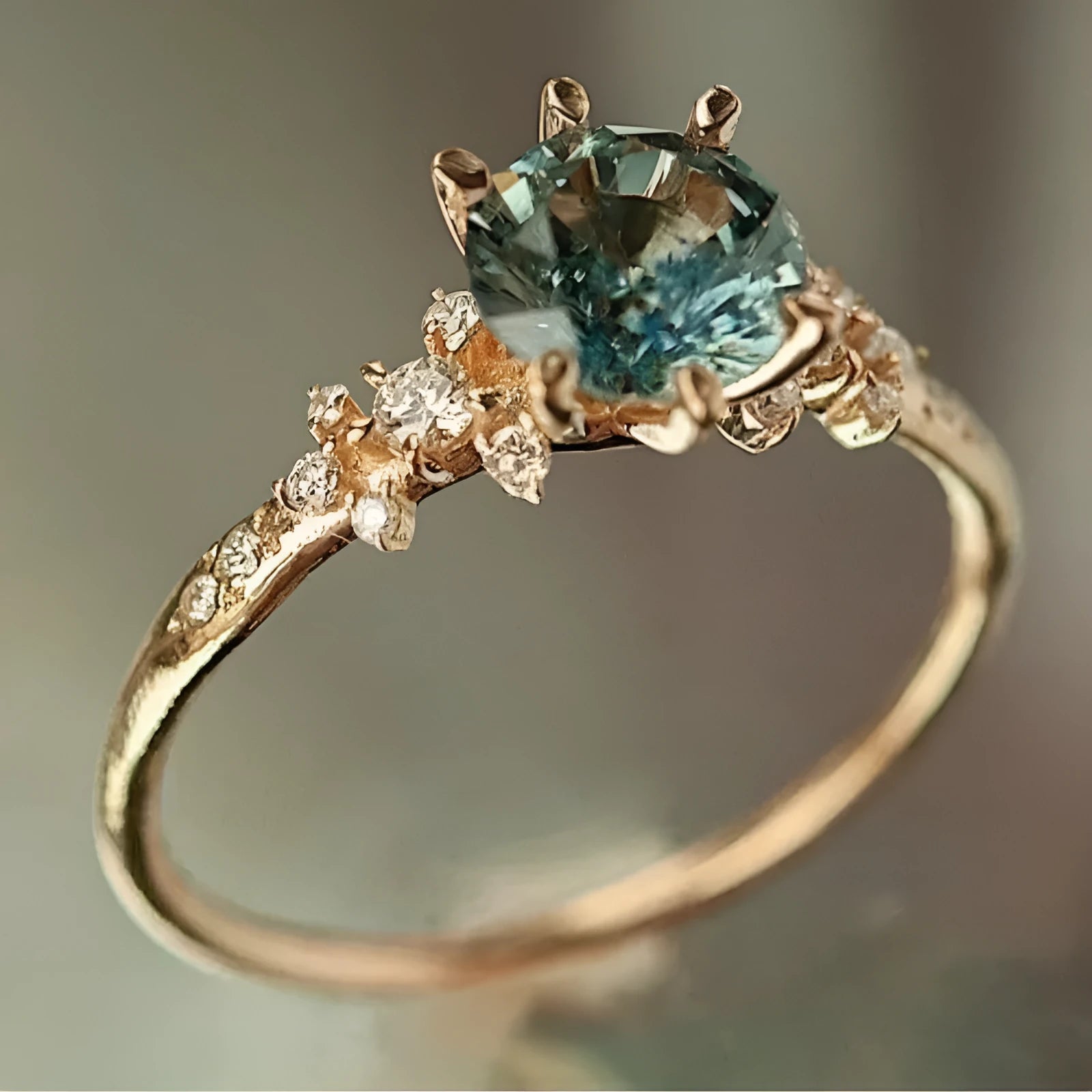 A gold-coloured geometric ring with a claw setting holding zircon stones on a chamfered square patterned band.