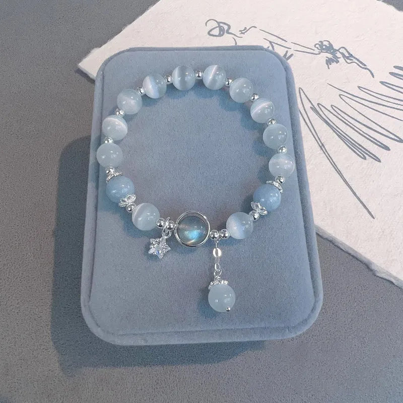 Close-up of a women's opal cat's eye stone beaded bracelet with diamond-shaped beads on a wrist.