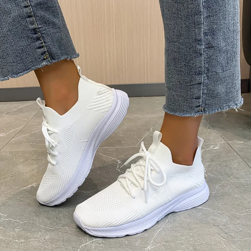 Women's low-top mesh running shoes in creamy white with a flat rubber sole and distinctive English muffin heel detail.