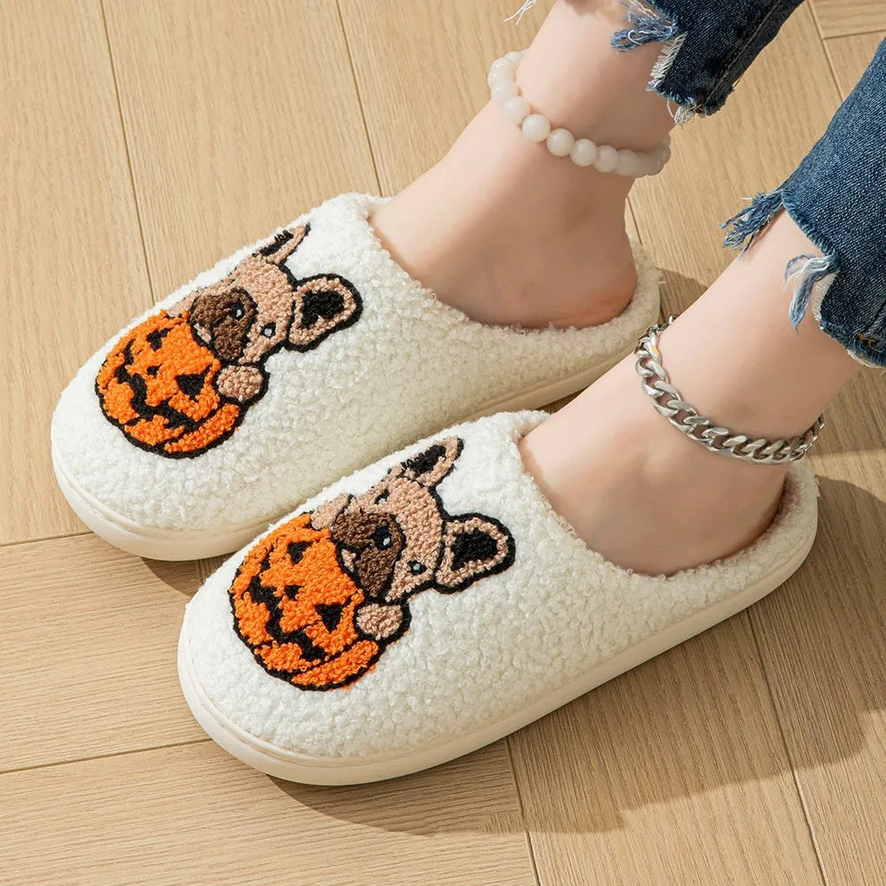 Pair of black plush house slippers with orange pumpkin print and a textured non-slip rubber sole.