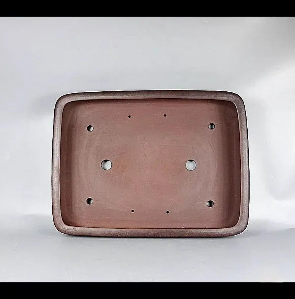 Large rectangular handmade antique purple clay flower pot on a table.