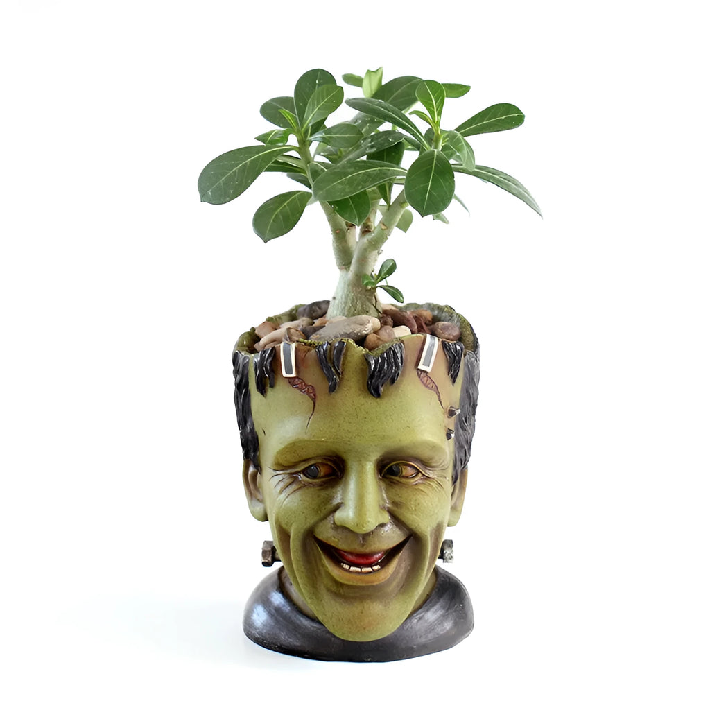 Green Frankenstein monster resin flower pot on a desk with a small succulent plant inside