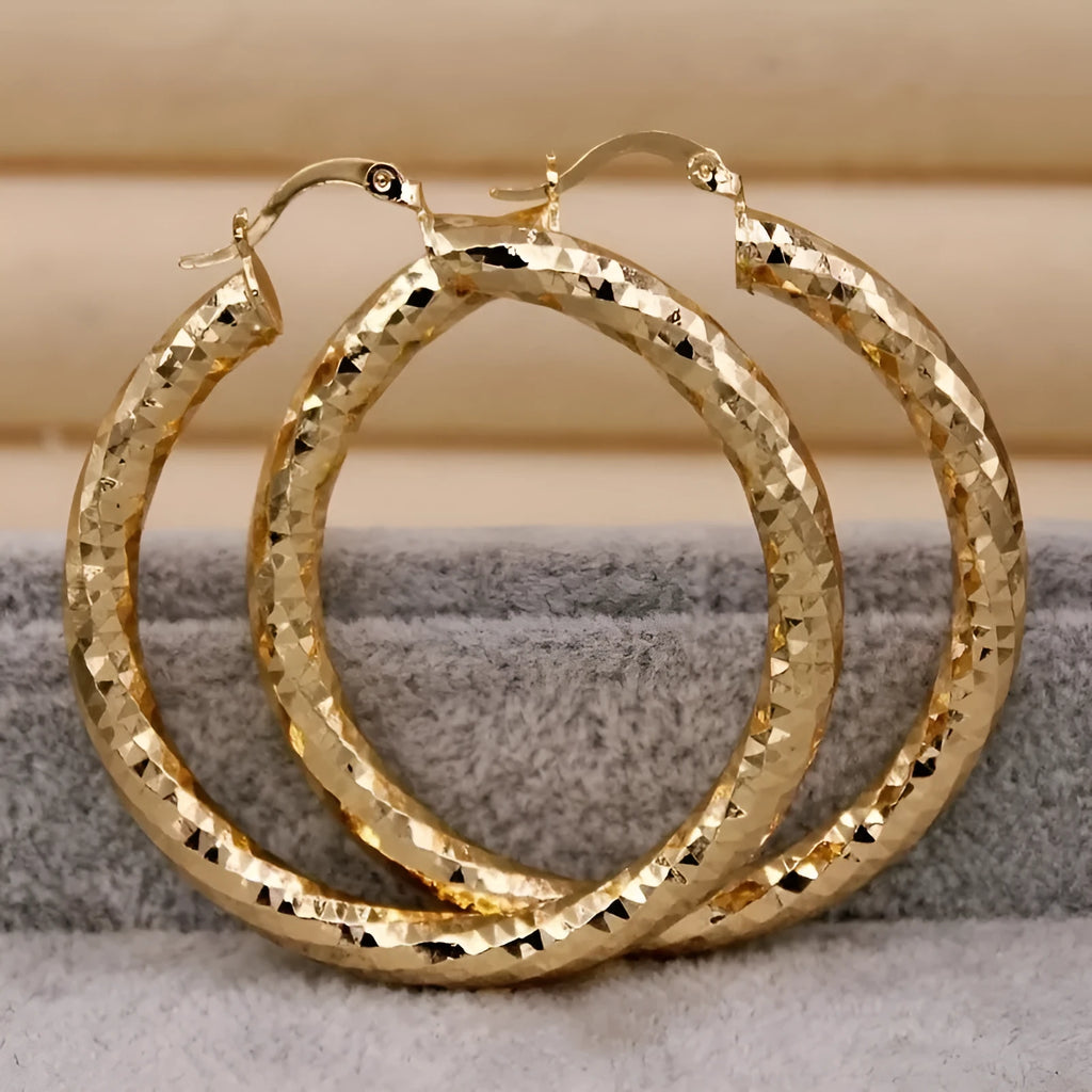 Pair of gold-coloured retro classic alloy earrings for women on a neutral background
