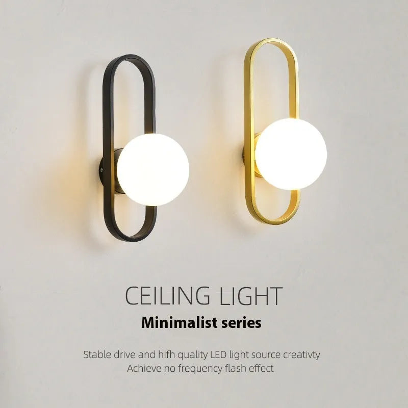 Minimalist wall-mounted lamp with clear glass bulb shade on a black iron sconce arm and backplate.
