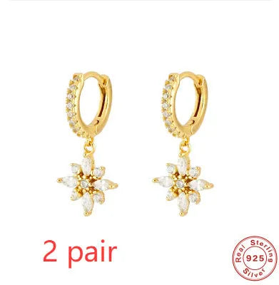 A pair of sterling silver snowflake pendant earrings with a gemstone, shown in yellow gold and white gold colour finishes.
