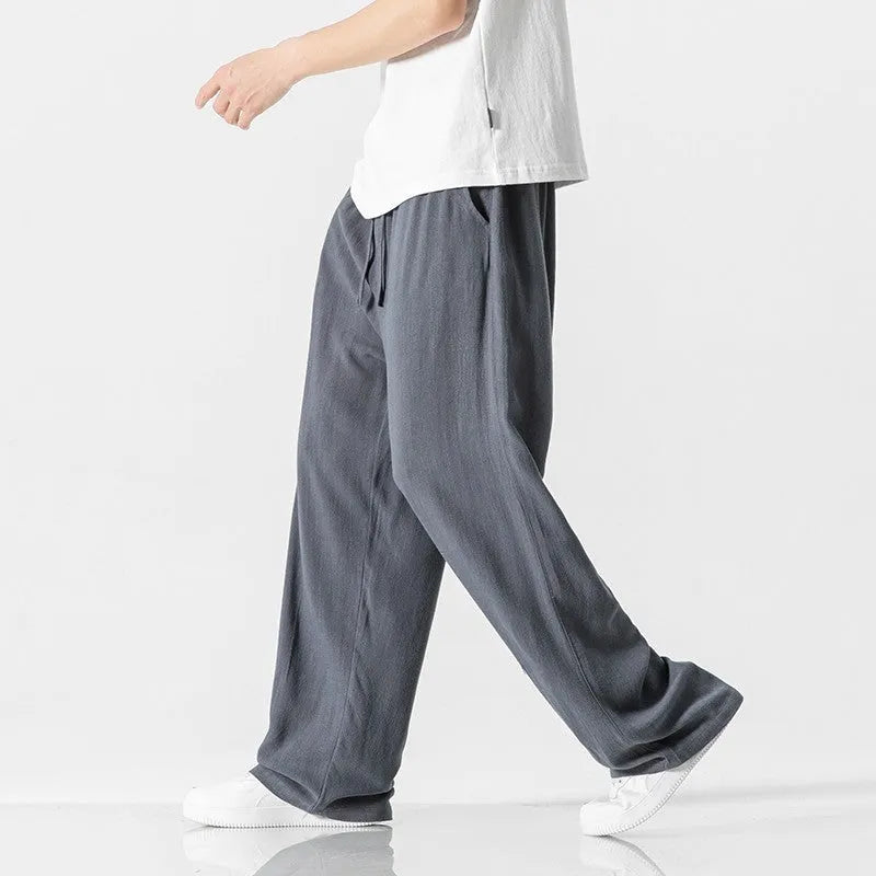 Man wearing beige cropped straight-leg bamboo fibre trousers with a drawstring waist on a summer day.