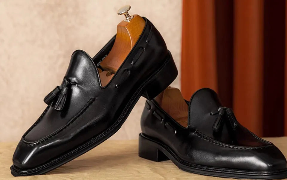 Men's black genuine leather loafers with a fringed detail and slip-on design.