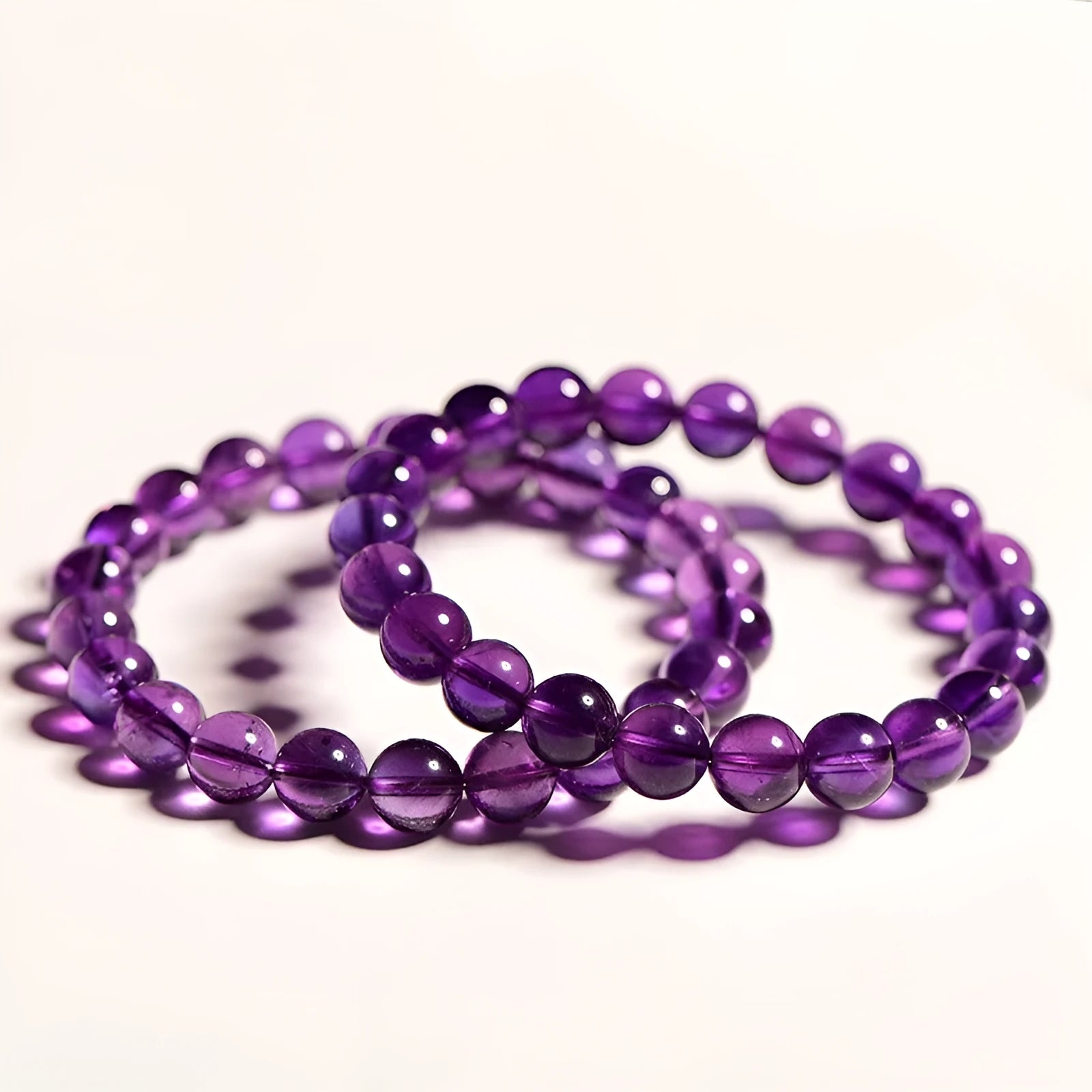 Close-up of a natural purple amethyst bead bracelet with elastic band on a wrist.