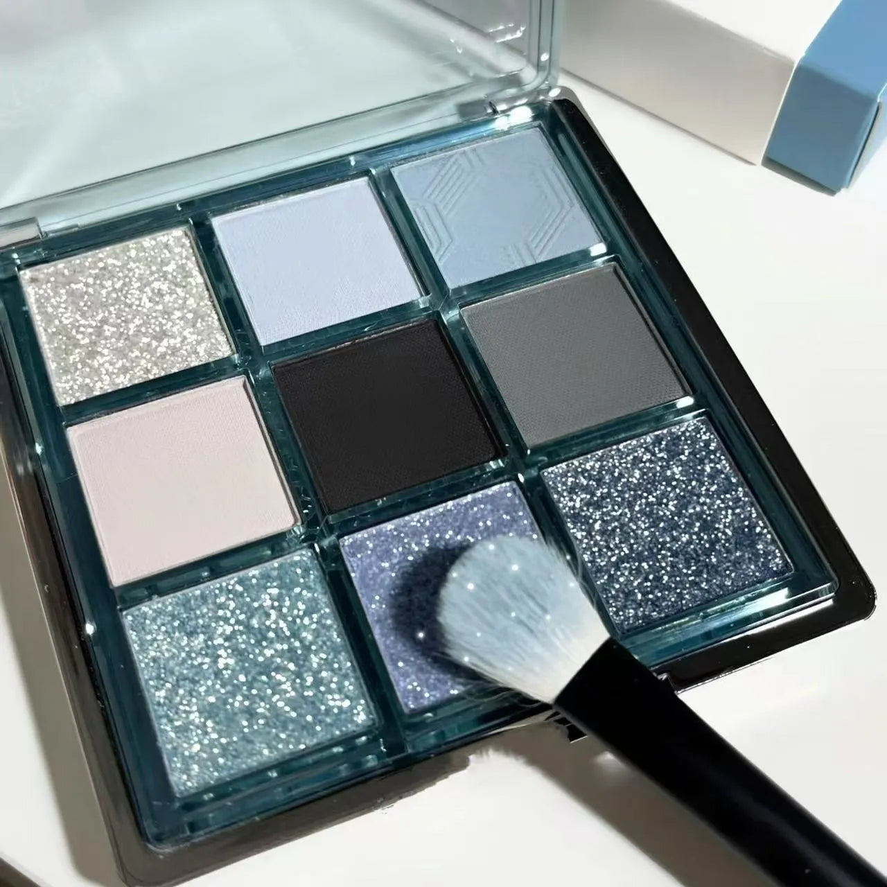 MUGELEEN nine-colour eyeshadow palette showing low saturation blue and earth tones with diamond debris effect