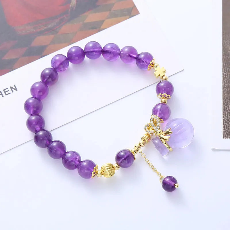 Purple amethyst crystal bracelet with money bag charm and peace buckle on woman's wrist