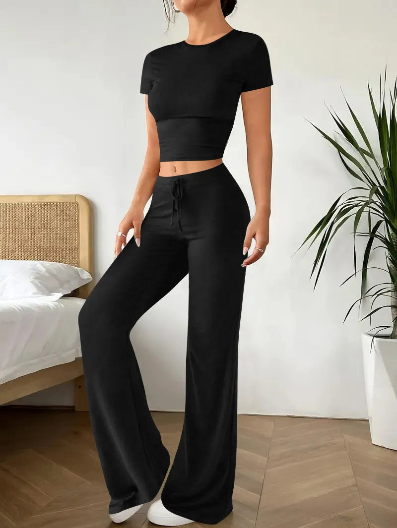 Black women's high waist trousers and short sleeve T-shirt lounge suit set on a plain background.