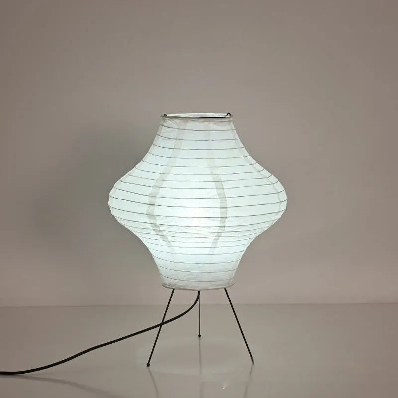 Japanese style table lamp with a white paper shade and a wooden base on a table.