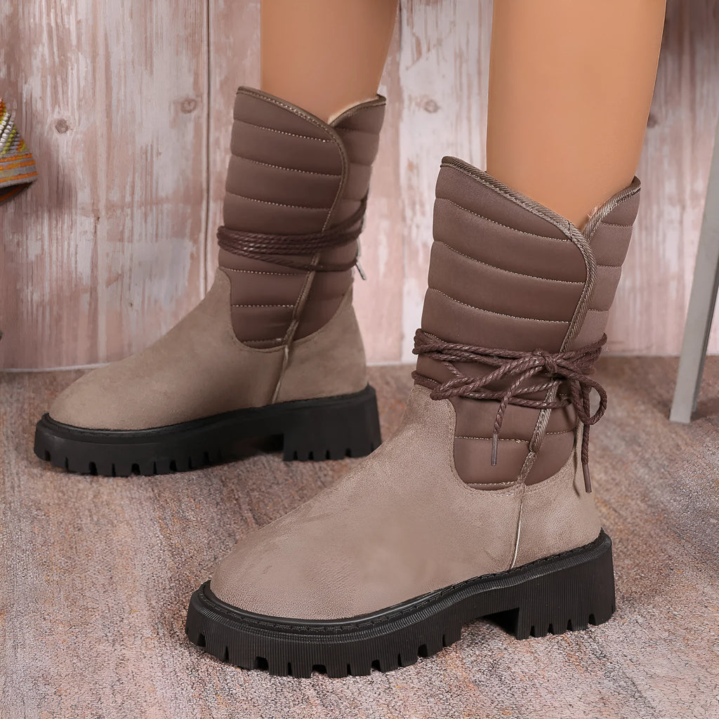A pair of women's chunky heel snow boots in suede with a lace-up front and fleece lining, shown in black.