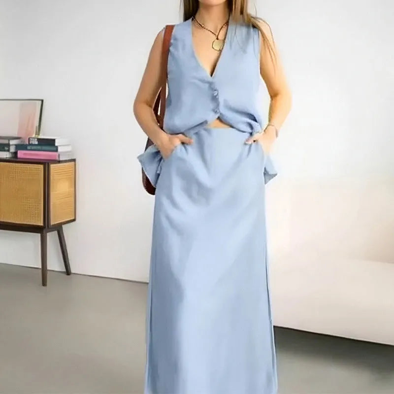 A woman modelling a blue sleeveless vest and matching long skirt from a casual two-piece suit.