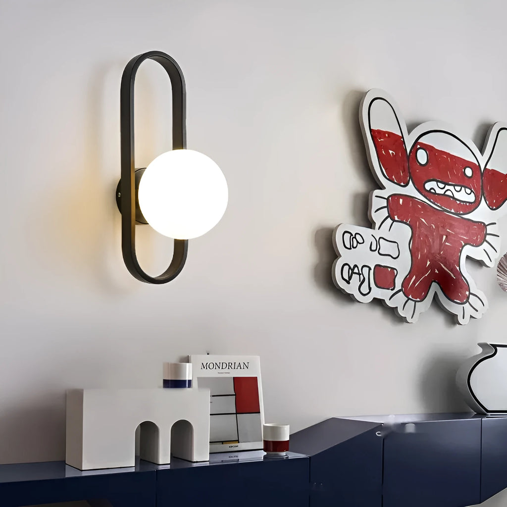 Minimalist wall-mounted lamp with clear glass bulb shade on a black iron sconce arm and backplate.