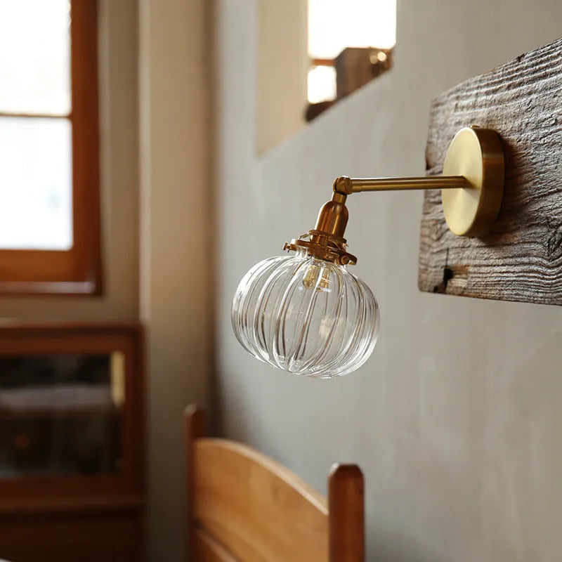 Close-up of a hand-blown water ripple glass wall lamp shade mounted on a white wall, showing its textured surface.