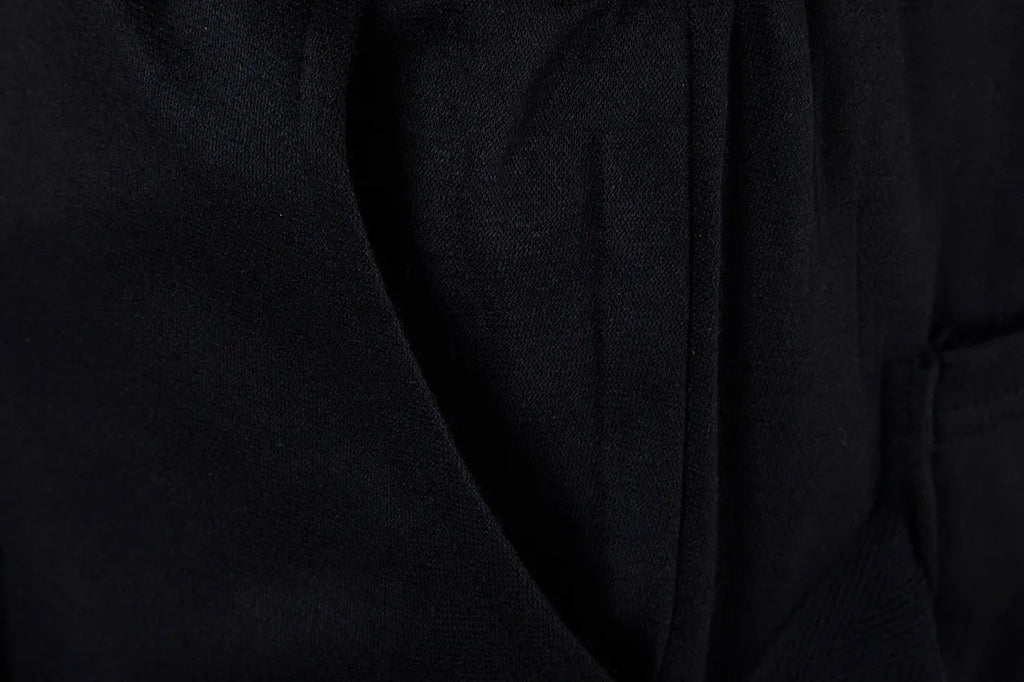 Men's black low crotch cross trousers with tapered cone leg and small hem on a plain background
